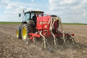A tractor pulls a dale drills seed drill through a field
