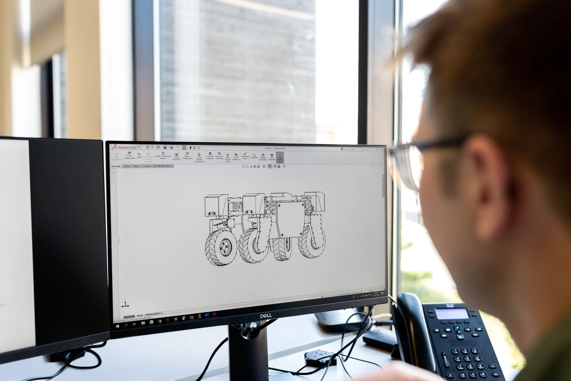 A Summit Engineer employee sits working at a computer using Solid Works 3D design software.
