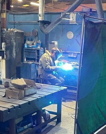 A welder with his visor down welding in the Summit Engineering workshop