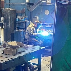A Summit Engineering employee with his welding mask down working in the workshop