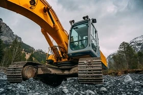 Yellow excavator driving over rubble